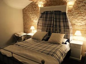 a bedroom with a bed with a headboard and two lamps at Le Logis de Limalonges in Limalonges