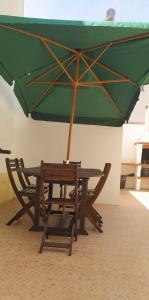 a picnic table with a green umbrella and chairs at Green House in Baleal