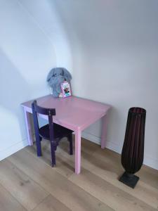 a teddy bear sitting at a pink table in a room at Chambres dans le gîte "Rêves de Gamins", proche du pôle Européen et du circuit des 24h in Sargé Les Le Mans 