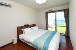 a bedroom with a bed and a large window at SEAVIEW VILLAS&HOUSE ONNA in Nakadomari