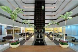 a lobby with palm trees in a building at LE JARDIN Suites in Caldas Novas