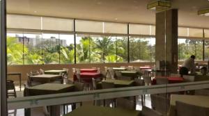 a dining room with tables and chairs and windows at LE JARDIN Suites in Caldas Novas