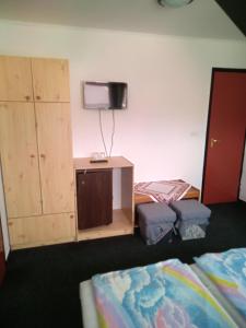 een kamer met 2 bedden en een tv aan de muur bij Napocska Panzió in Vonyarcvashegy