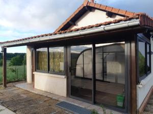 una extensión a una casa con ventanas de cristal en maison a la campagne avec piscine, en Flayat