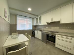 a kitchen with white cabinets and a table and chairs at Cedemar 1 in Cedeira