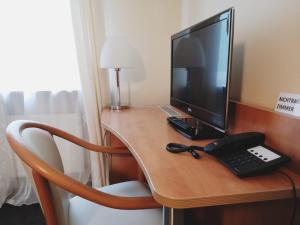 a desk with a computer monitor and a telephone on it at Hotel Meuser in Wiesbaden