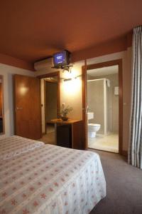 1 dormitorio con 1 cama y TV en la pared en Hotel Igartza, en Beasain