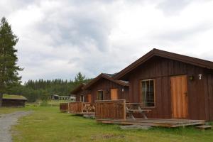 eine Holzhütte mit einer Veranda auf einem Feld in der Unterkunft Jotunheimen Feriesenter in Heidal