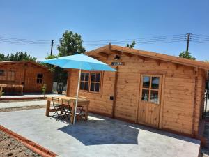 a wooden shed with a table and an umbrella at Cyprus Glamping Park in Ayios Theodhoros