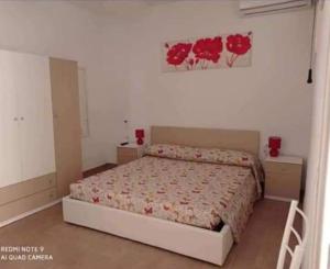 a bedroom with a bed with red flowers on the wall at Casa Vico Lepre in Noto