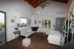 a living room with white furniture and windows at Kalamakia House-stylish cottage near Petani beach in Lixouri