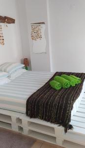 Una cama blanca con almohadas verdes encima. en Green House, en Baleal