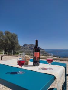 a bottle of wine sitting on a table with two glasses at Hotel Pranos Turismo Rurale Cala Gonone in Cala Gonone