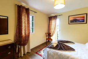um quarto com uma cama, uma televisão e uma janela em Villa Rústica - Casa da Lurdes em Ribeira Brava