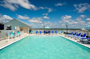 une piscine avec des chaises bleues et une terrasse dans l'établissement Hotel Monte Carlo Ocean City, à Ocean City