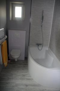 a bathroom with a white tub and a toilet at Maison dans le bourg in La Chapelle-Montligeon