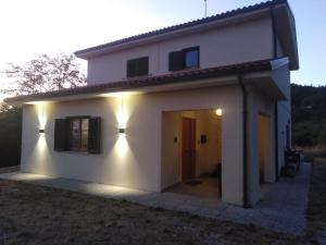 una casa bianca con una porta e luci di Casa Umbria a Gubbio