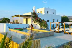 Paros House Villa في Pounda: امرأة تقف بجانب مسبح