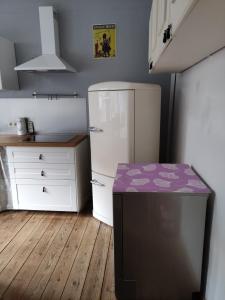 a kitchen with a white refrigerator and a wooden floor at Logies l'Epicerie de Durbuy appartement in Durbuy