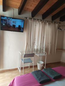 a bedroom with a table and a tv on the wall at Pension Azahar in Seville