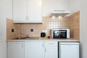 a kitchen with white cabinets and a microwave at Corfu Amboti Apt in Glyfada