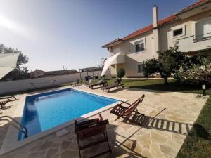 a swimming pool with two chairs and a house at Apartment Amelie - with pool and sauna! in Galovac