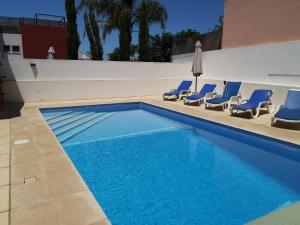 een zwembad met blauwe stoelen en een parasol bij Villa Arade Ferragudo in Ferragudo