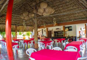 un restaurante con mesas rojas y sillas blancas en Cabañitas del Mar by Rotamundos, en Coveñas