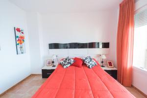 a bedroom with a red bed with two pillows at Expoholidays-Ático primera línea Aguadulce in Aguadulce