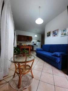 een woonkamer met een blauwe bank en een tafel bij Domo Vèdele in Galtellì
