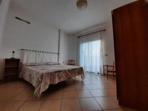 a bedroom with a bed and a large window at Domo Vèdele in Galtellì