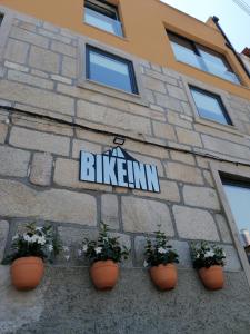 a sign on the side of a building with plants at BIKEINN in Vouzela
