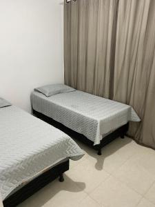 カマサリにあるApartamento Guarajubaのカーテン付きの客室で、ツインベッド2台が備わります。