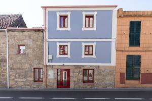 un edificio azul con puertas rojas en una calle en A Casa Antiga do Monte Apartamentos Turísticos - Lestrove, en Padrón