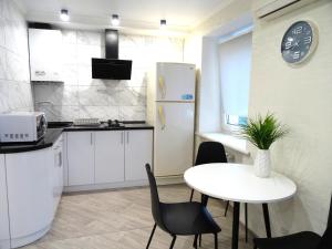 a kitchen with a white table and a white refrigerator at Apart Gagarina 7 in Kropyvnytskyi