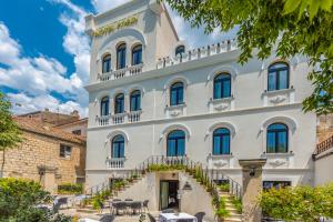 Un grand bâtiment blanc avec des escaliers se trouve juste devant. dans l'établissement Heritage Hotel Porin Makarska, à Makarska