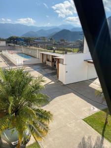 a building with a swimming pool and a palm tree at Apartamento Aconchegante Sun Way in Ubatuba