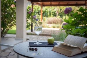a glass of wine sitting on a table with an apple and an open book at Syvota Gardens in Syvota