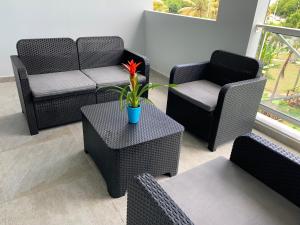a patio with chairs and a table with a flower on it at Karaibes Residence in Le Gosier