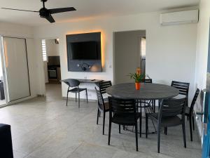 uma sala de jantar com uma mesa e cadeiras e uma televisão em Karaibes Residence em Le Gosier