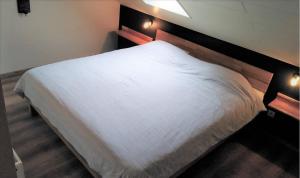1 dormitorio con cama blanca y cabecero de madera en Point Escale en Lontzen
