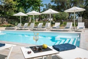 a table with a glass of wine next to a swimming pool at Syvota Gardens in Syvota