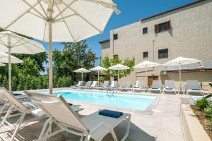 a swimming pool with white chairs and umbrellas at Syvota Gardens in Syvota