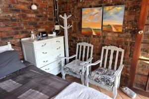 a bedroom with two chairs and a bed and a dresser at Riverstay in Kroonstad