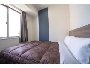 een slaapkamer met een bed en een groot raam bij R&B Hotel Hakata Ekimae 2 - Vacation STAY 40725v in Fukuoka
