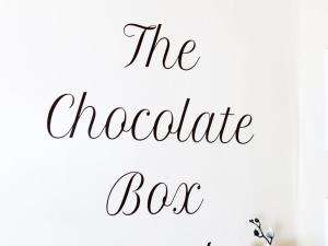 un cartel que dice la caja de chocolate en una pared blanca en The Chocolate Box Hotel, en Bournemouth