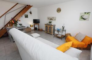 sala de estar con sofá blanco y muebles de color naranja en Les Figuets, en Châteauneuf-de-Galaure