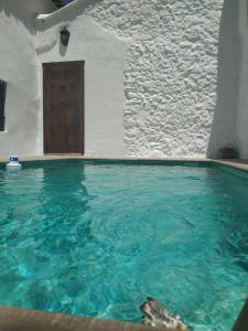 einem Pool mit blauem Wasser vor einem Gebäude in der Unterkunft Casa El Villa in Zahara de la Sierra