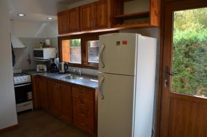 a kitchen with a white refrigerator and a sink at La Araucaria in Villa La Angostura +10 photos