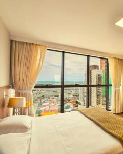 um quarto com uma grande cama branca e uma grande janela em Hotel 7 Itajaí em Itajaí